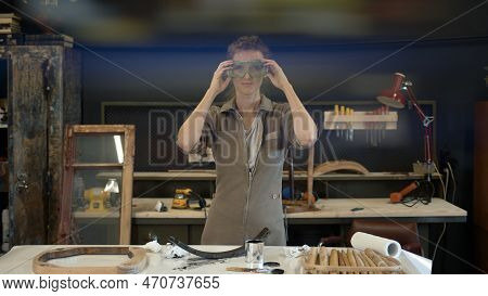 Woman Putting On Safety Glasses, Middle Shot In The Workshop. Young Woman In Worksuit Put On Goggles