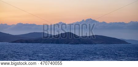 Rocky Island On Mediterranean Sea. Rinia Near Mikonos, Greece, Europe. Nature Background. Sunrise Sk