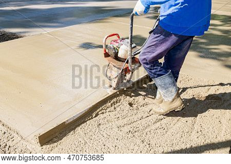 Construction Worker Is Wearing Gloves As Leveling Fresh Concrete With Motor Power Tool, Vibration Me