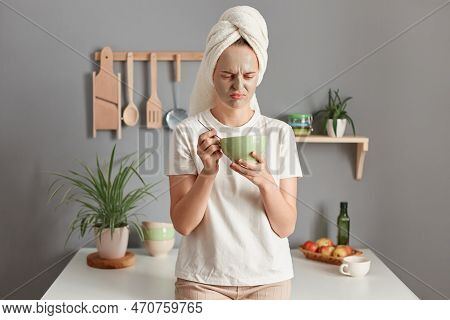 Indoor Shot Of Sad Upset Young Adult Woman Wrapped White Towel And Dressed In T-shirt Standing Near 