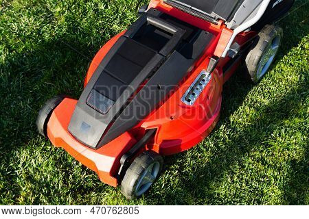 Electric Lawn Mower On A Green Meadow. Garden Equipment.