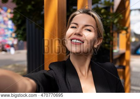 Middle-aged Woman Takes A Selfie In The Rays Of The Sun During The Day In The City