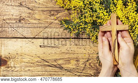 Easter Holiday Religion Card. Womans Hands Hold Wooden Crucifixion On Wooden Background With Mimosa 