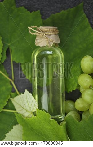Grape Vinegar. Oil In A Transparent Bottle And Green Grapes With Leaves On A Gray Slate Background.g