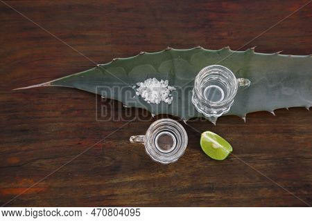 Mexican Tequila Shots, Salt, Lime Slice And Green Leaf On Wooden Table, Flat Lay. Drink Made Of Agav