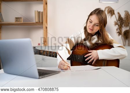 Young Caucasian Female Composer Man Composing Song Using Guitar And Laptop At Home. Copy Space