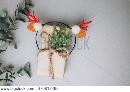 A Gift Wrapped In Brown Paper And Decorated With A Thuya Branch And Deer Antler On A Gray Concrete B