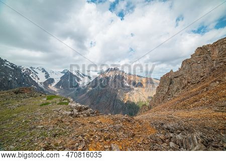 Vivid Mountain Landscape Near Precipice Edge With Sharp Stones With View To Sunlit Large Pinnacle Wi
