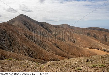 Shapes And Lines Of The Mountains Of The Volcanic Origin. Light Brown Color Of The Soil. Sky With Cl
