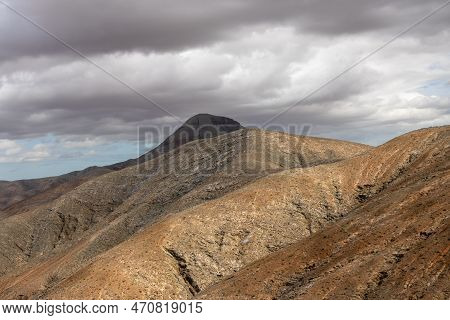 Shapes And Lines Of The Mountains Of The Volcanic Origin. Light Brown Color Of The Soil. Sky With Cl