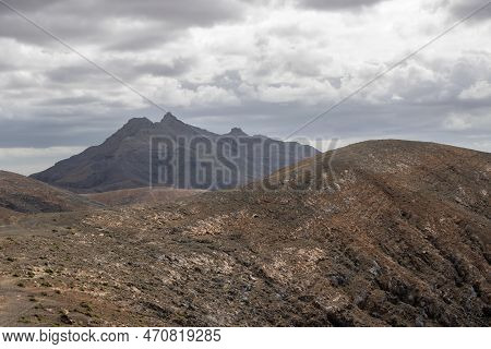 Shapes And Lines Of The Mountains Of The Volcanic Origin. Light Brown Color Of The Soil. Sky With Cl