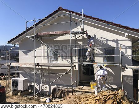 Fischbach, Germany - March 8, 2022: New Construction Site With Finished Base Plaster, Worker At Scaf