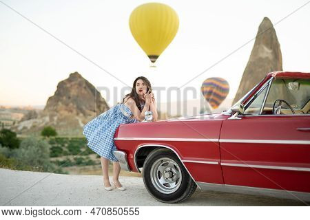 Beautiful Girl In Retro Style Posing Near A Vintage Red Cabriolet Car On Background Of Balloons In C