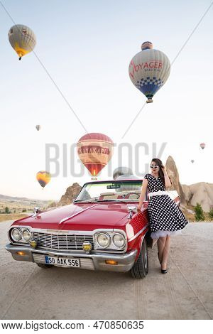 Goreme, Turkey, Cappadocia- June 30, 2021: Beautiful Girl In Retro Style Posing Near A Vintage Red C