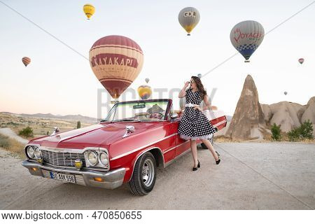 Goreme, Turkey, Cappadocia- June 30, 2021: Beautiful Girl In Retro Style Posing Near A Vintage Red C