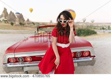 Beautiful Girl In Retro Style Posing Near A Vintage Red Cabriolet Car On Background Of Balloons In C