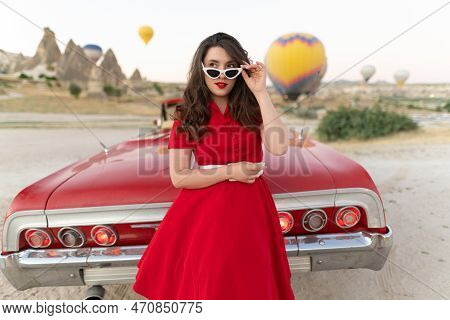Beautiful Girl In Retro Style Posing Near A Vintage Red Cabriolet Car On Background Of Balloons In C