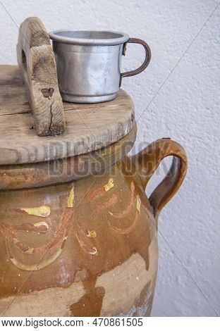 Large Earthenware Jar With Lid And Aluminum Cup For Drinking Water. Old Cottage Kitchen Concept