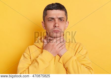 Portrait Of Ill Man With Dark Hair Wearing Casual Style Hoodie Standing Isolated Over Yellow Backgro