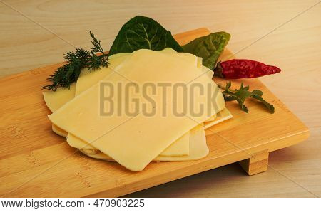 Sliced Cheese With Herbs On The Wooden Bckground