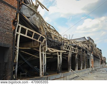 A Warehouse With A Loading Ramp After A Fire. Burnt Metal Frame Of The Building. Consequences Of The