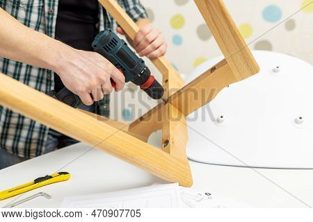 Assemble Furniture. Man Assembling Chair. Furniture Assembler With Drill