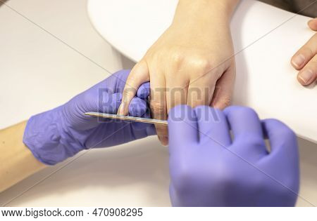 Manicurist Shapes, Files Beautiful Womans Nails, Holding Finger. Caucasian Manicure Master Works In 