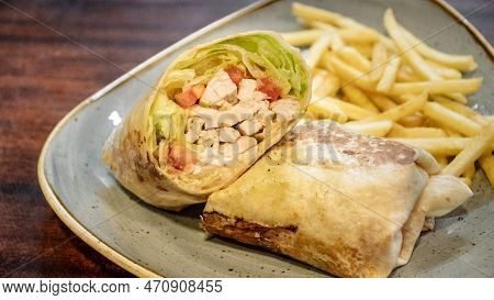 A Tasty Image Of A Freshly Prepared Chicken Tortilla Wrap Filled With Salad And Served With French F