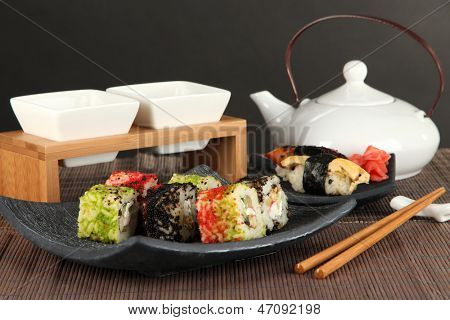Velsmagende Maki sushi - Roll på grønne blade på bordet på grå baggrund