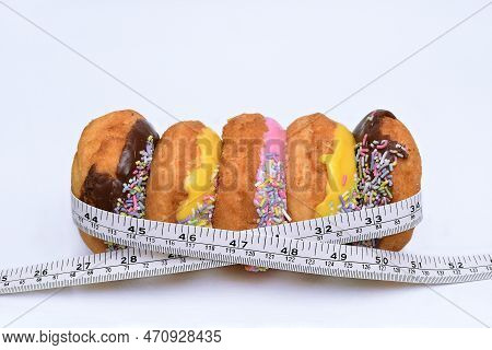A Measuring Tape Wrapped Around Five Colourful Doughnuts To Illustrate How Too Much Junk Food Can Ca
