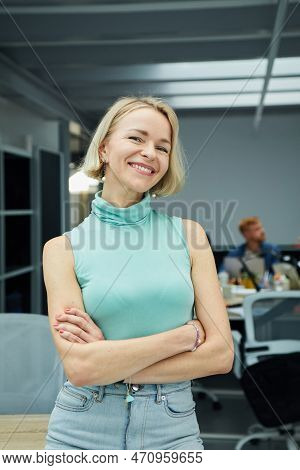 Vertical. Smiling Caucasian Business Woman Looking At Camera Standing With Arms Crossed In Office.