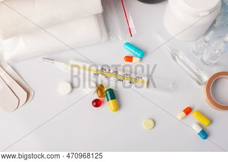 Medical Thermomether Between Pills And Other Medical Appliences Of First Aid Kit On White Table