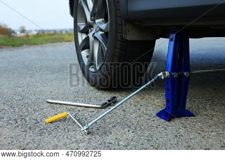 Car Lifted By Scissor Jack Without Wheel Outdoors, Closeup. Tire Puncture