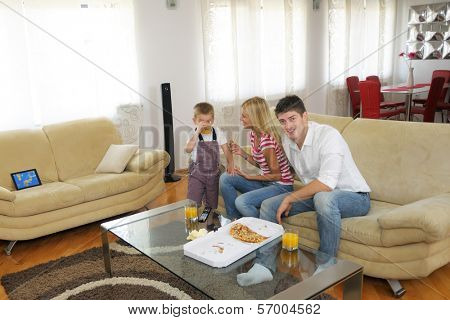 happy young family eating tasty pizza with cheesa and dring healthy and fresh orange juice