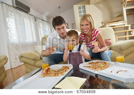 happy young family eating tasty pizza with cheesa and dring healthy and fresh orange juice