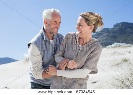 Attractive couple messing about on the beach on a bright but cool day