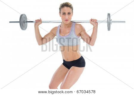 Strong female crossfitter lifting barbell behind head looking at camera on white background