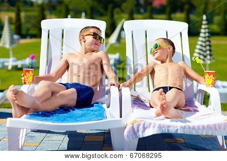 Teenage Boys Relaxing On Sunbeds In Waterpark