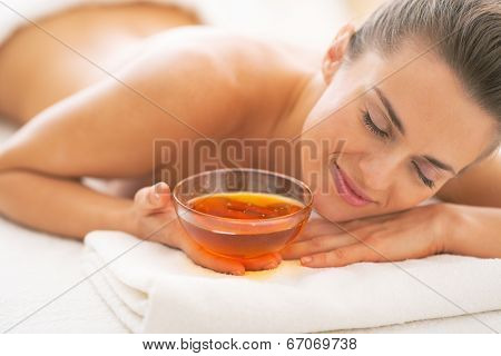 Relaxed Young Woman Laying On Massage Table With Honey Plate