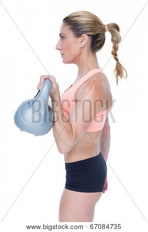 Female blonde crossfitter lifting kettlebell on white background
