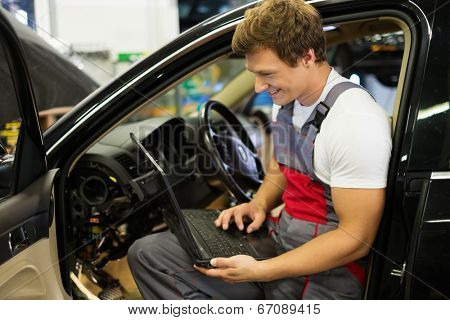 Serviceman making car diagnostics with laptop in a workshop