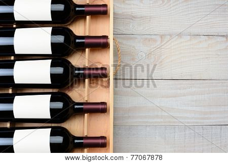 High angle shot of a case of red wine bottles with blank labels  on a rustic white wood table with copy space. Horizontal format.