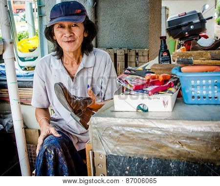 Old woman at her shoe shine stand in Singapore
