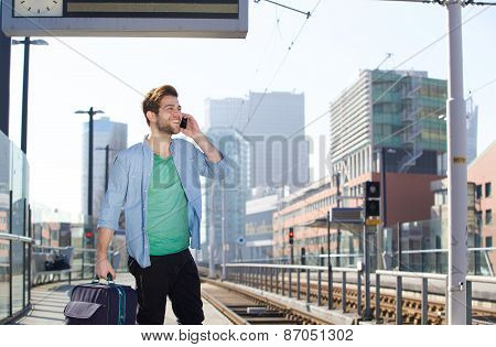 Happy Young Man Talking On Mobile Phone At Train Station Platform