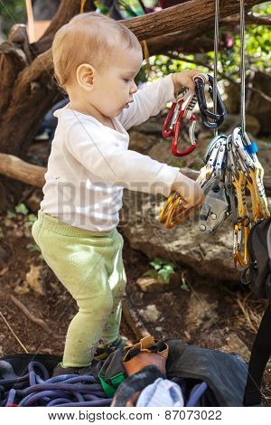 Child of rock climbers playing with quickdraws