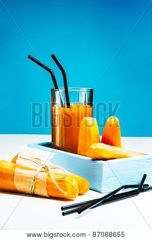 Freshly squeezed carrot juice in the glasses.A box with purified carrot on a blue wooden background.