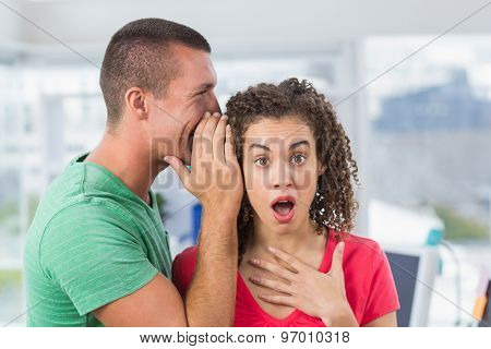 Casual businessman whispering secret to his colleague in the office