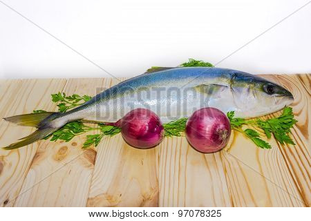 Whole Round Fish Yellowtail And Red Onion On A Wooden Surface