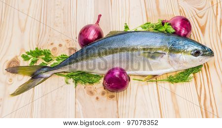 Whole Round Fish Yellowtail And Red Onion On A Wooden Surface
