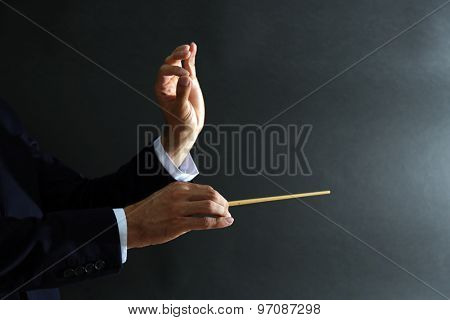 Music conductor hands with baton on black background